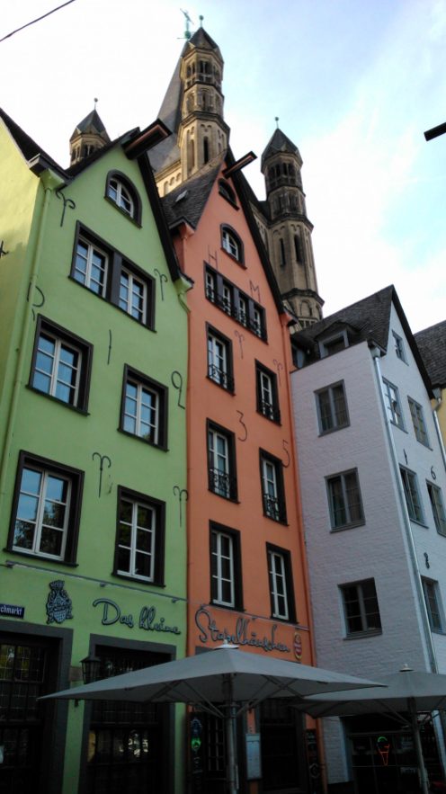Drei bunt bemalte, schmale Häuser mit spitzen Dächern in der Kölner Altstadt.