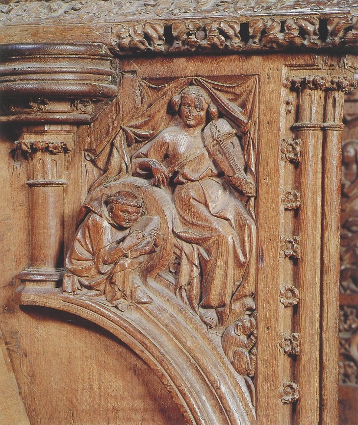 Foto einer Holzschnitzerei, die im Chorgestühl des Kölner Doms zu sehen ist. Gezeigt werden zwei musizierende und mit Instrumenten ausgestattete Figuren.