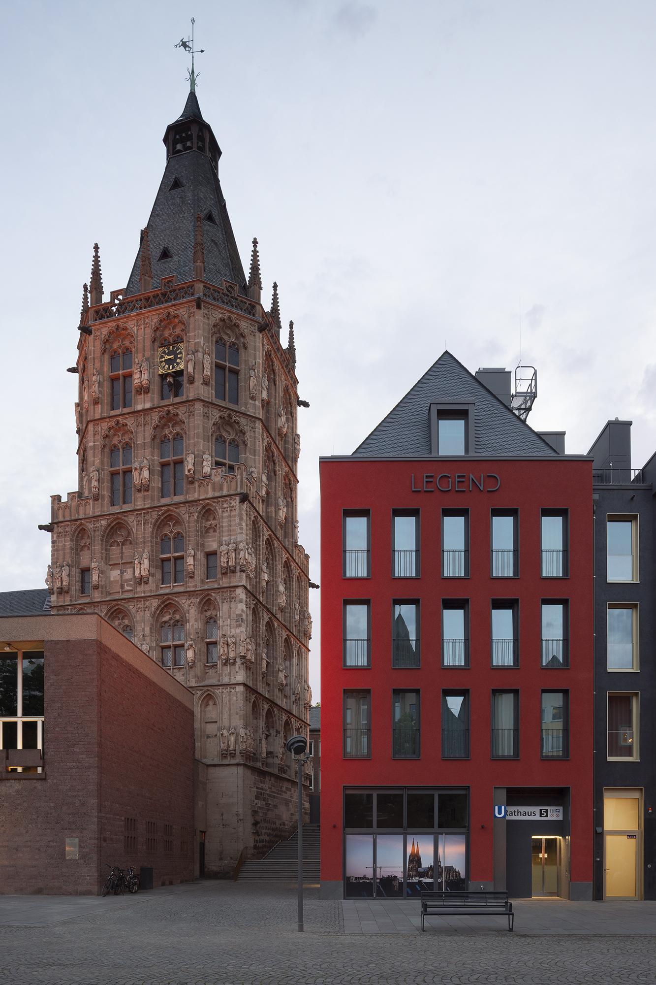 Ein signalrotes Haus am Alter Markt in Köln. Links daneben das Rathaus mit dem historischen Rathausturm